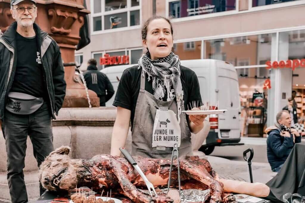 PETA Streetteam mit Schildern und Hundeatrappe auf einem Grill.