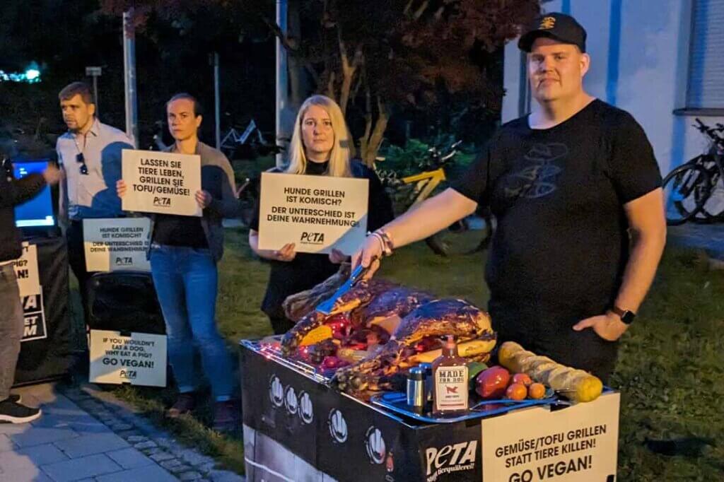 PETA Streetteam mit Schildern und Hundeatrappe auf einem Grill.