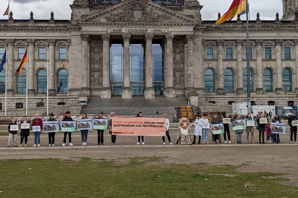 Demonstrierende gegen Tierversuche stehen mit Schildern und Bannern auf einer Strasse.