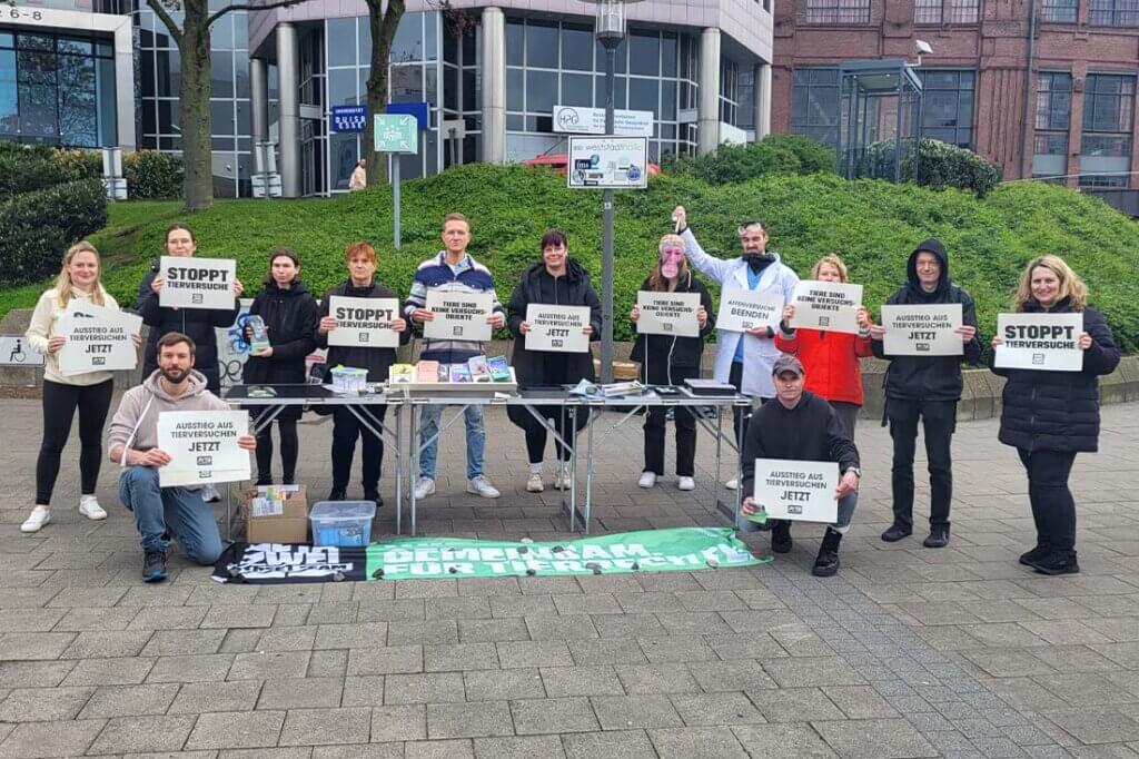 Demonstrierende gegen Tierversuche stehen mit Schildern und Bannern auf einer Strasse.