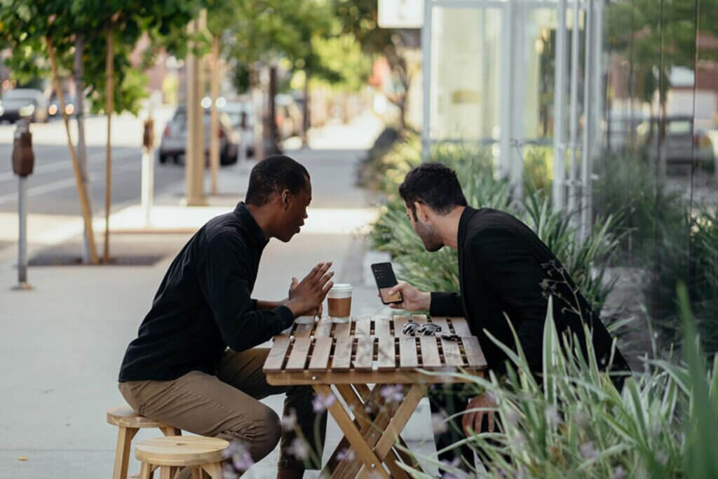 Männer sitzen draußen an einem Tisch und reden