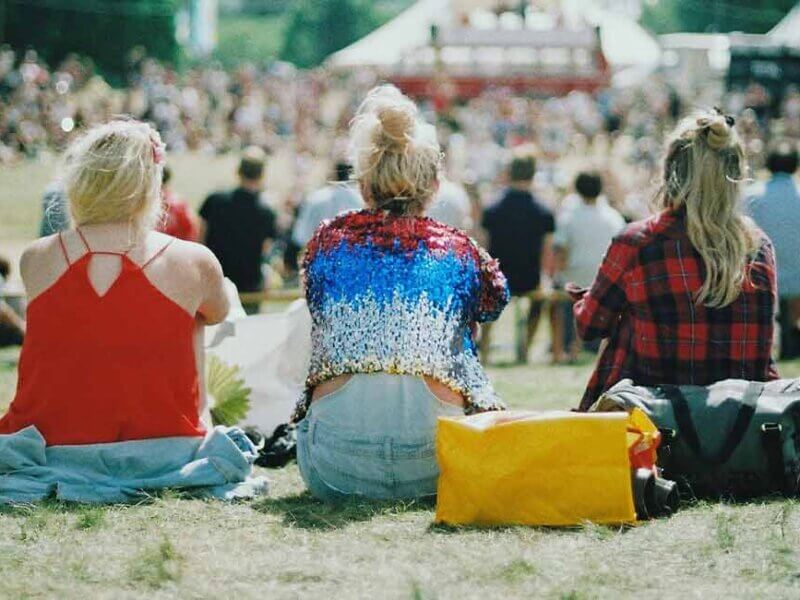 Menschen sitzen auf einem Festival auf einer Wiese