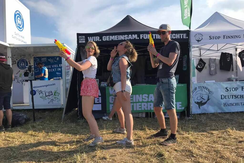 Drei Aktive auf einem Festival mit Wasserpistolen.
