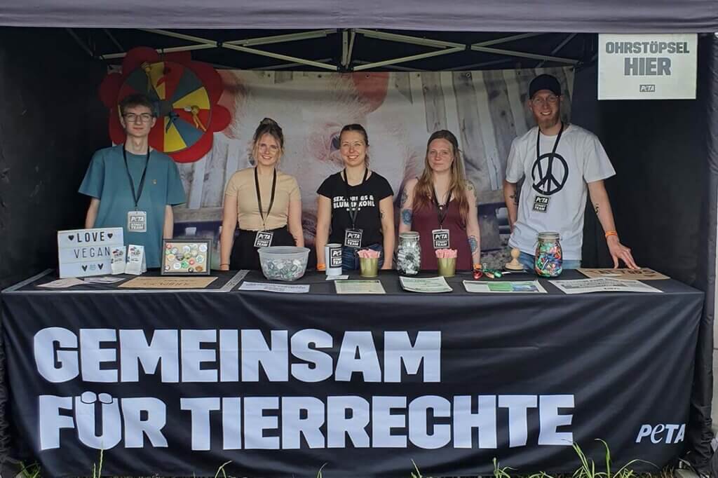 Menschen stehen hinter dem PETA Stand.