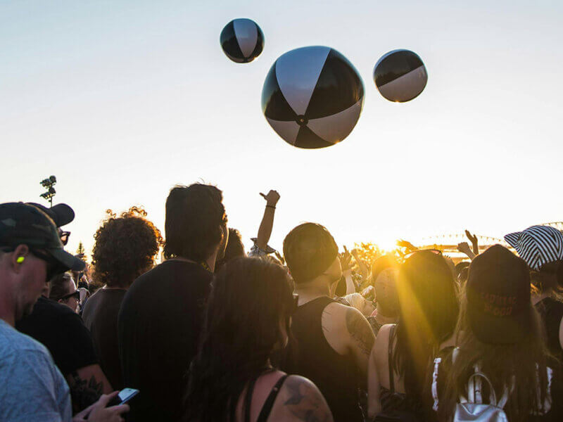 Menschenmenge auf einem Festival mit Bällen, die herumgeworfen werden im Sonnenuntergang